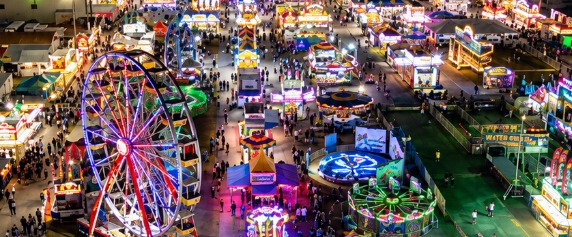 Aerial night view of the Pensacola Interstate Fair midway with a lit Ferris wheel and carnival rides