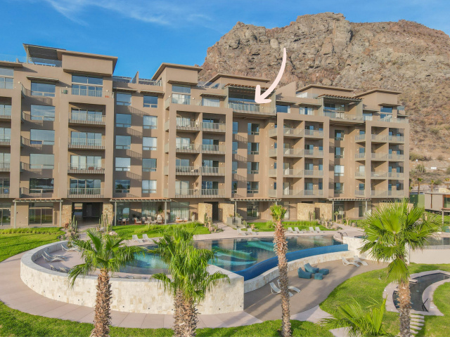 Mantarraya Residences building exterior with pool, palm trees, and mountain backdrop at Danzante Bay