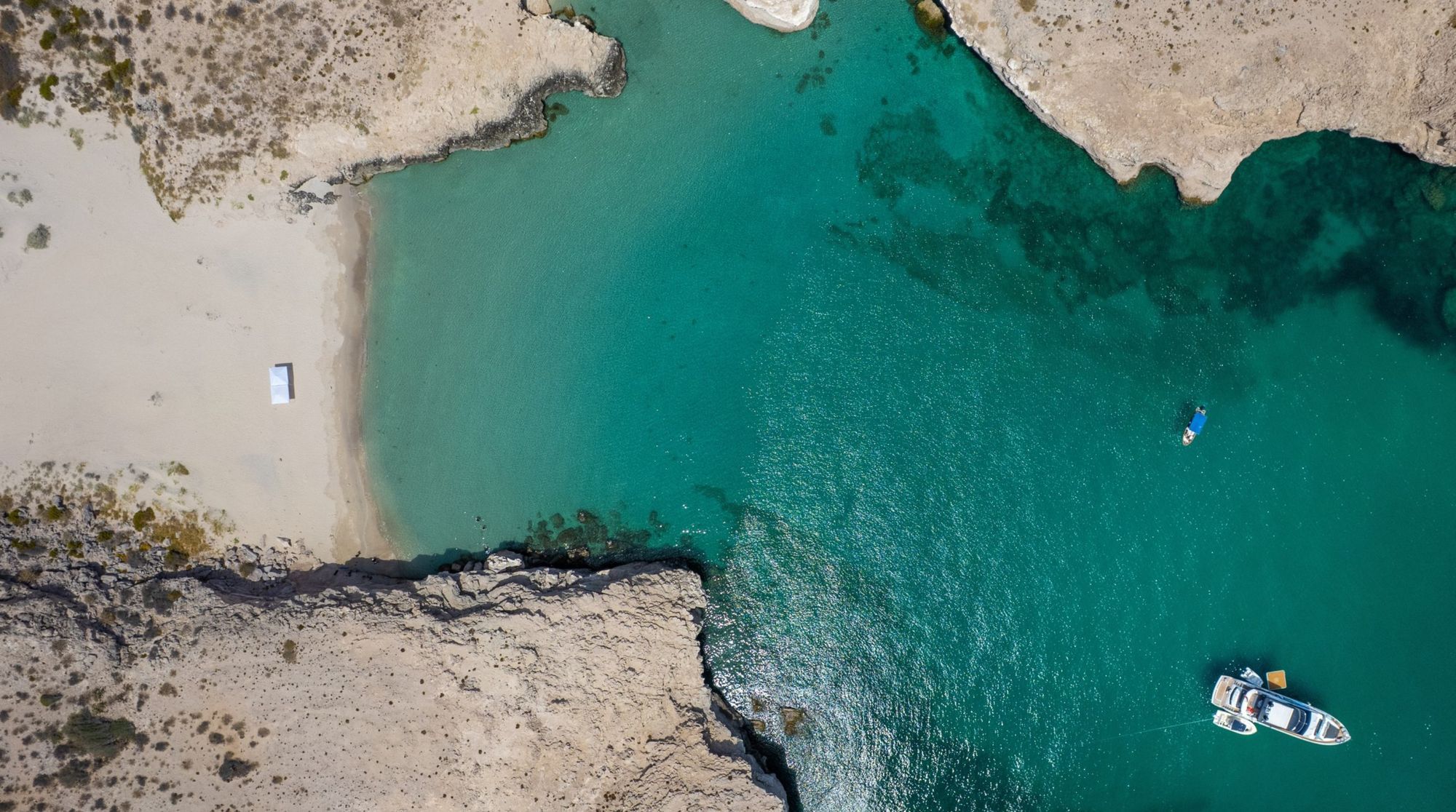 Aerial view of Isla Danzante showing a secluded sandy cove with two boats anchored in clear turquoise water